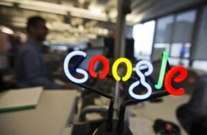A neon Google logo is seen as employees work at the new Google office in Toronto